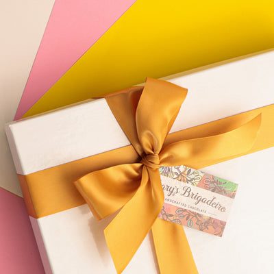 White gift box with a yellow ribbon on a colorful background